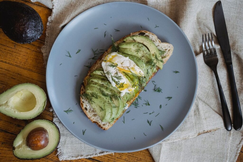 Avocado toast topped with a poached egg and dill on a gray plate