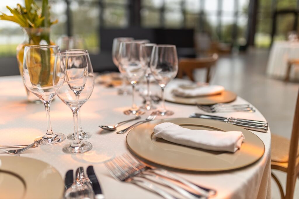 Banquet table set with wine glasses, folded napkin and gold charger plate
