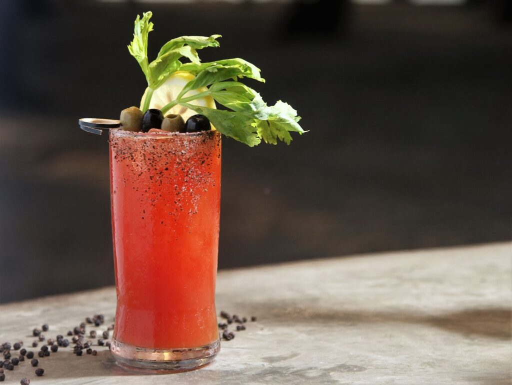 Bloody Mary cocktail garnished with celery and olives in a tall glass