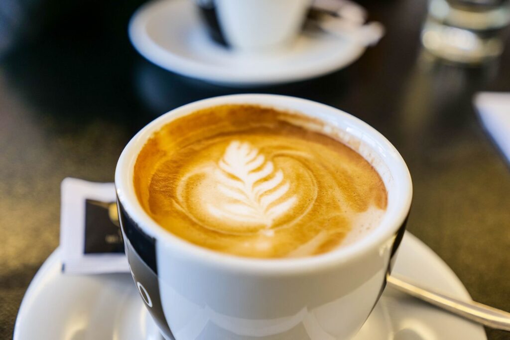 Cappuccino with rosetta latte art in a white cup on a saucer