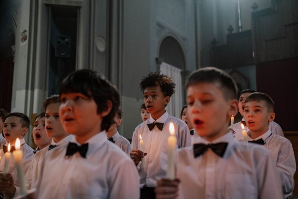 Choir members in white shirts holding candles inside a church