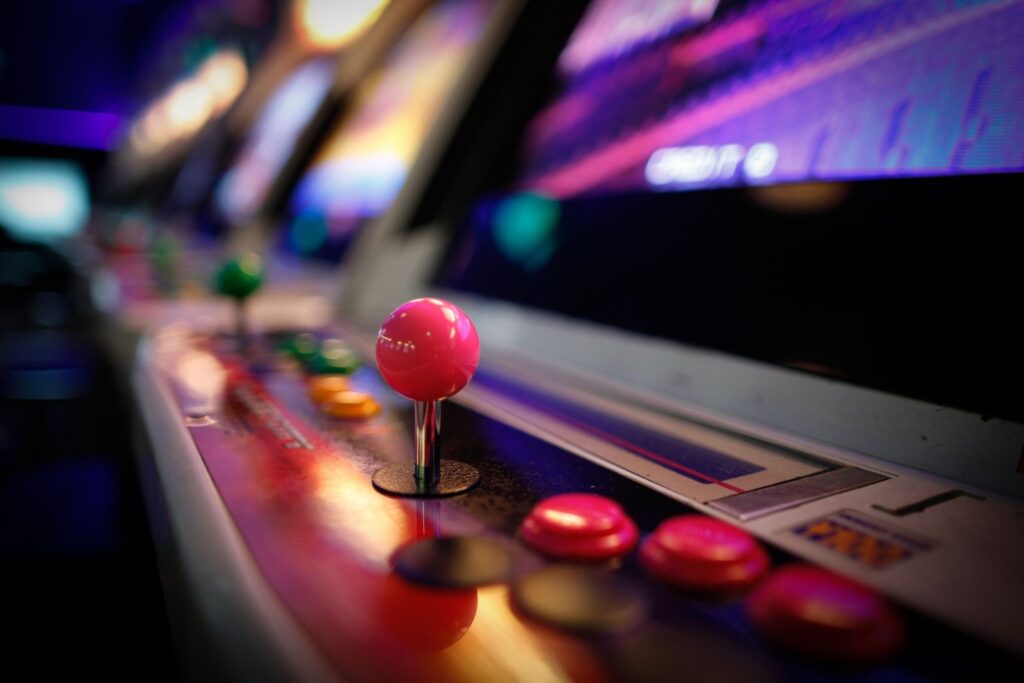 Close-up of a vintage arcade machine with a red joystick and glowing buttons