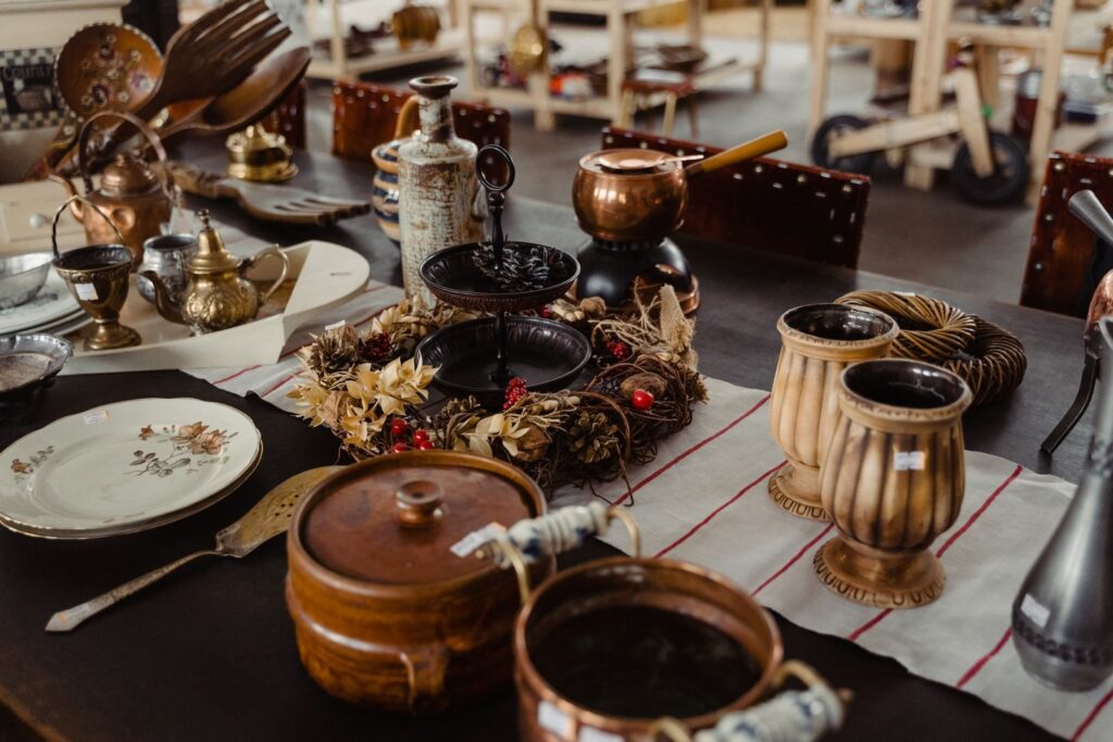 Copper pots, vintage plates and antique kitchenware laid out on a shop table