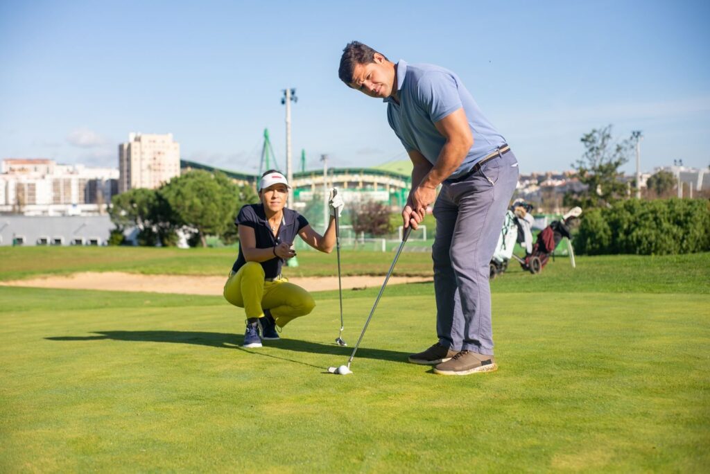 Couple lining up a putt together on a sunny golf green