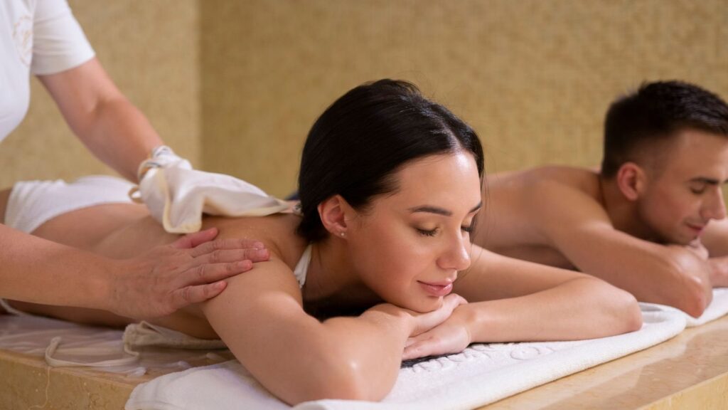 Couple lying side by side during a massage in a softly lit spa room