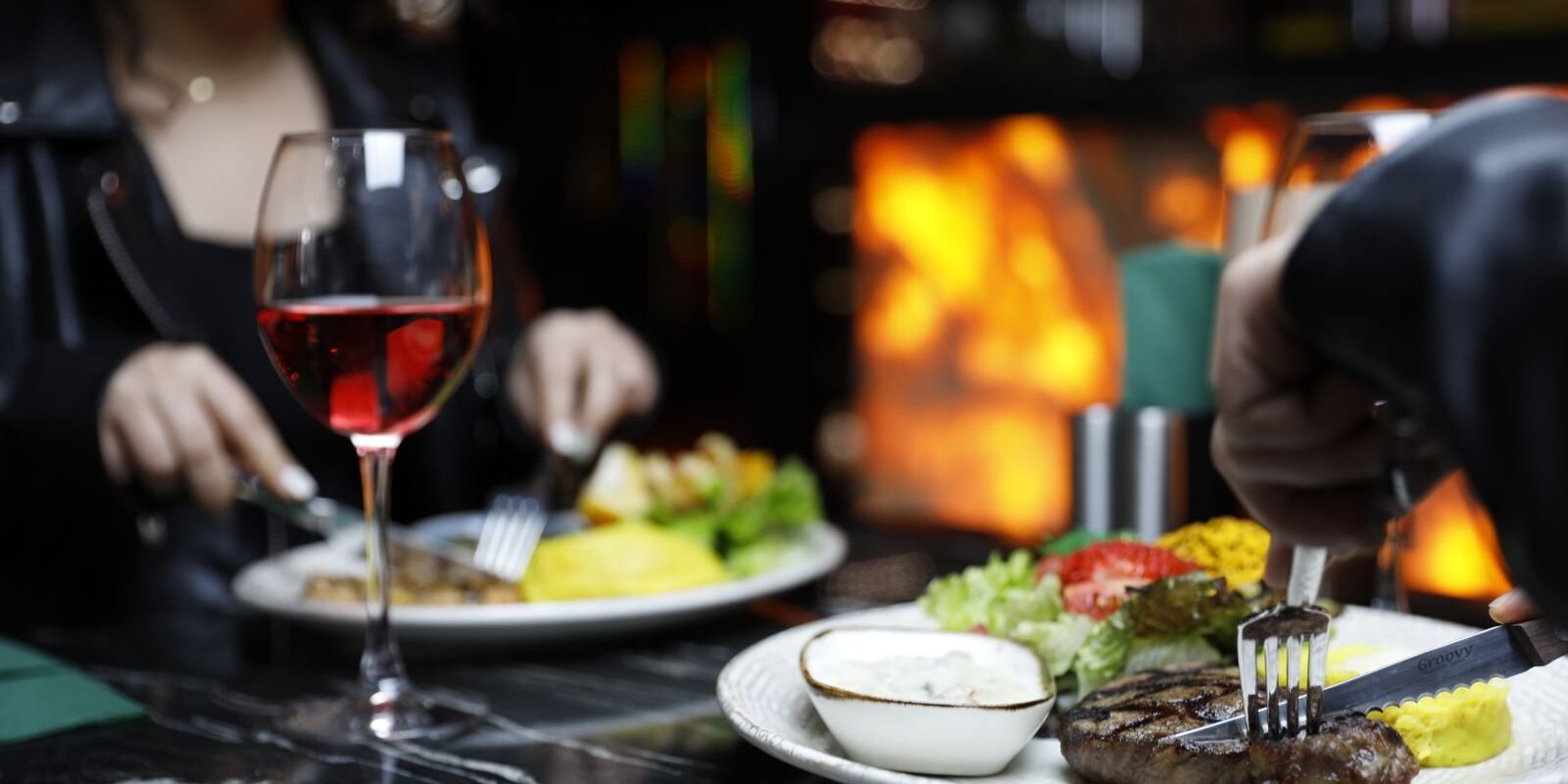 Couple sharing a steak dinner and red wine at a candlelit restaurant table