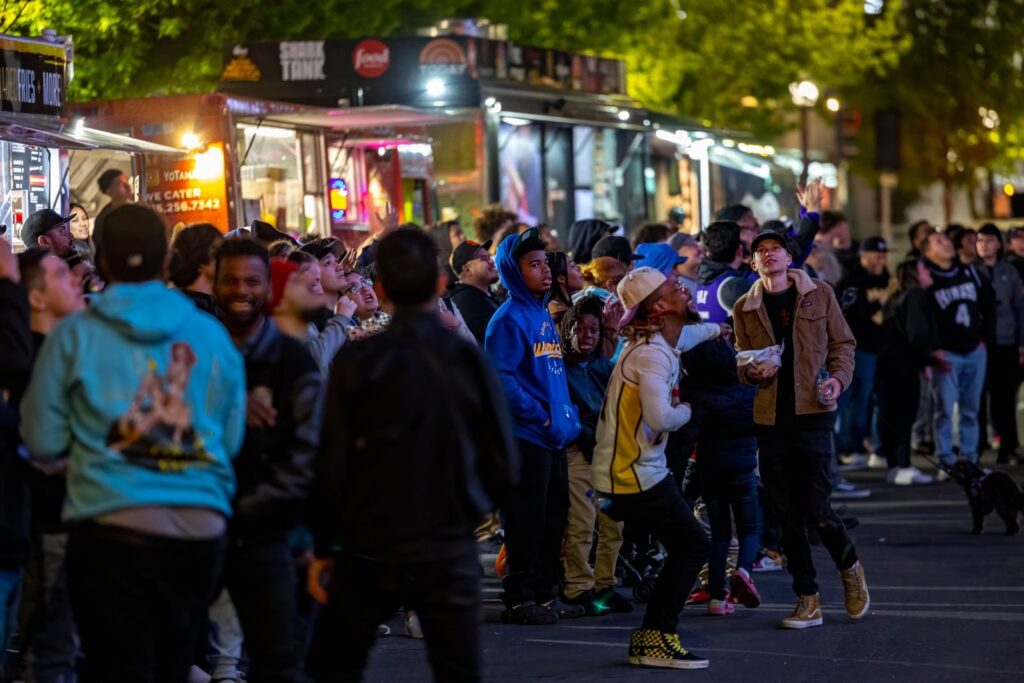 Crowd gathered around lit food trucks at an evening street festival