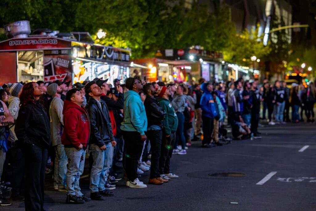 Crowd lining up along a street at an evening food truck festival