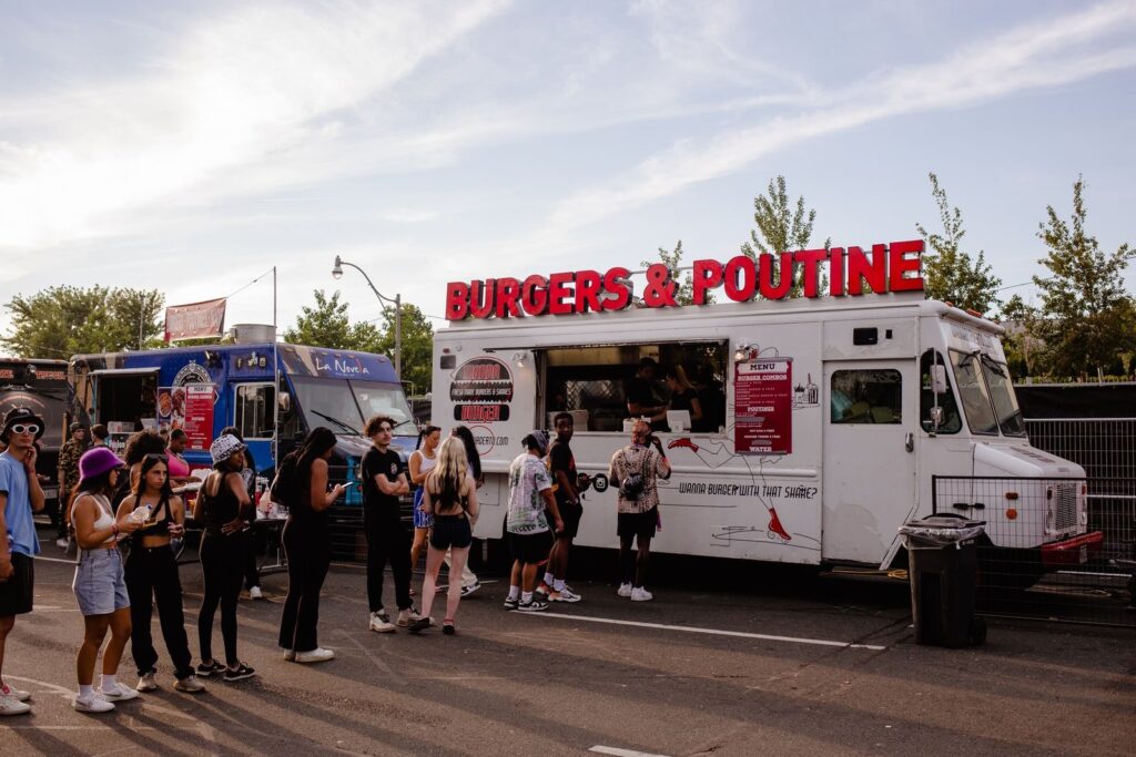 Crowd lining up at a burger food truck at an outdoor festival