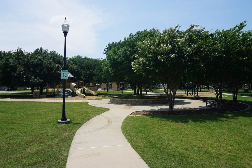 Curving park path with a lamppost and playground in Youth Center Park, Frisco