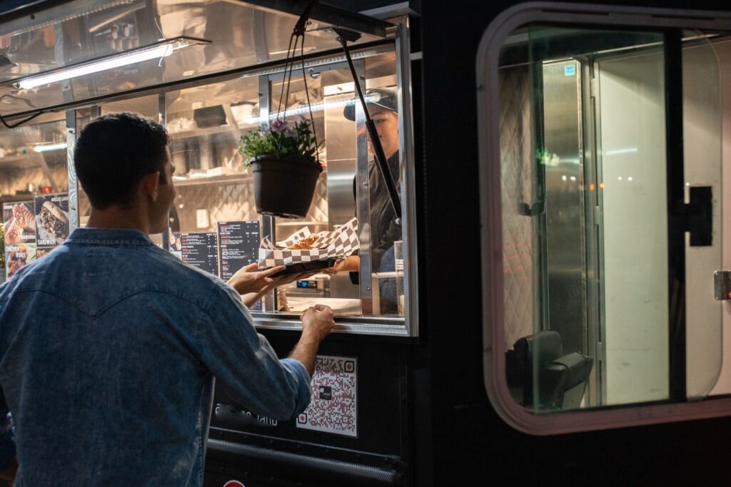 Customer ordering from the window of a food truck at night