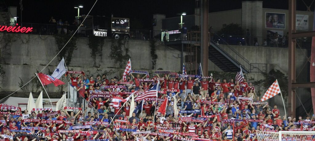 Dallas Beer Guardians supporters waving flags and scarves in the Toyota Stadium stands