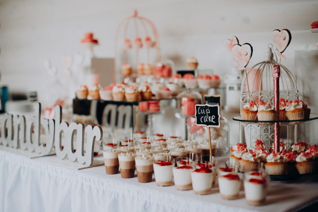 Dessert table with cupcakes, small glasses of sweets and flowers at a party