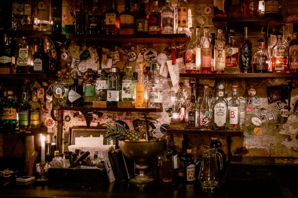 Dimly lit back bar lined with liquor bottles, candles and vintage decor