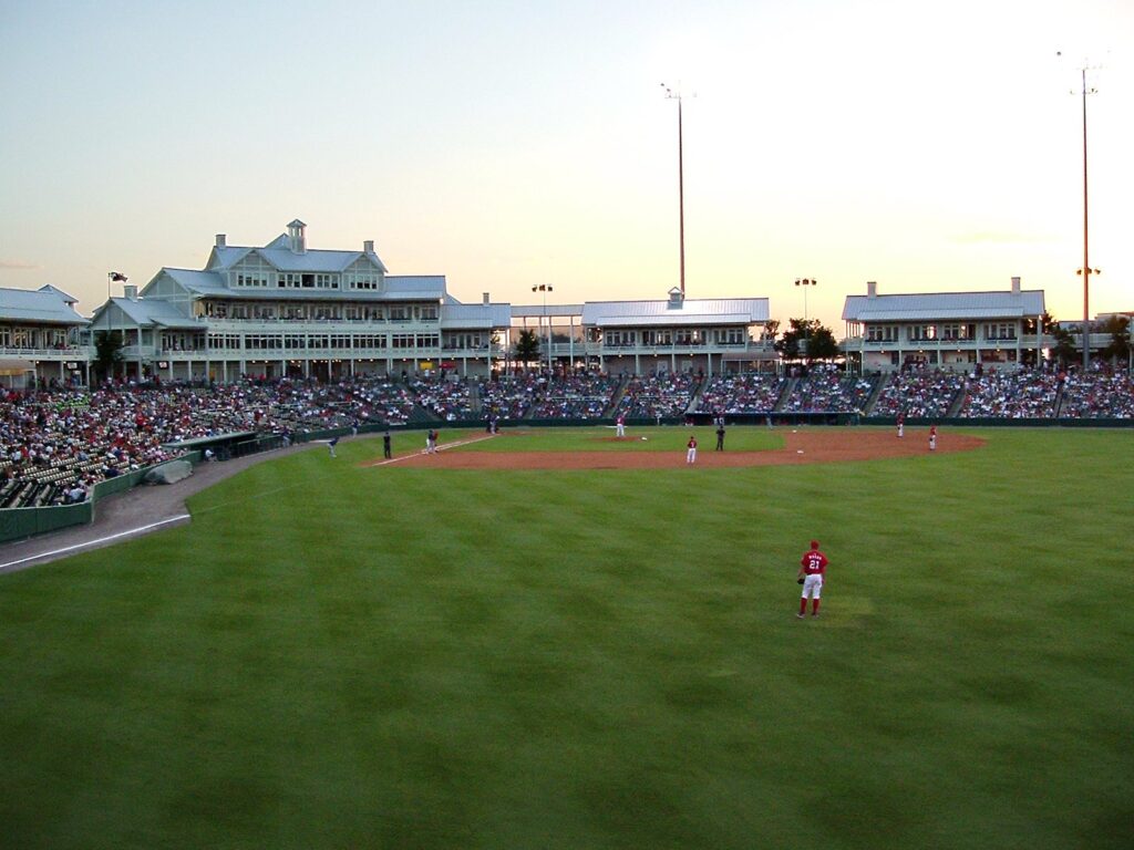 Evening crowd at a Frisco RoughRiders game seen from the outfield grass