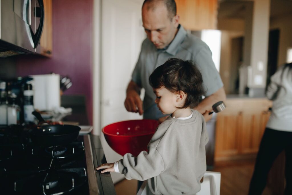 Father and young son cooking together at a home kitchen stove