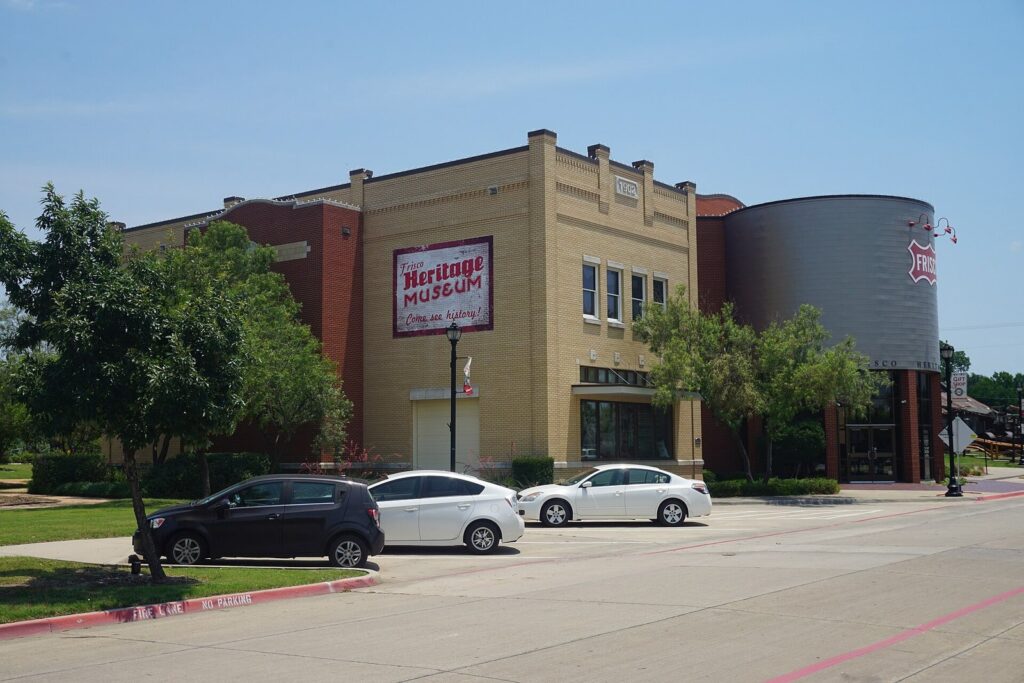 Frisco Heritage Museum, a tan brick building with a round tower beside a parking lot
