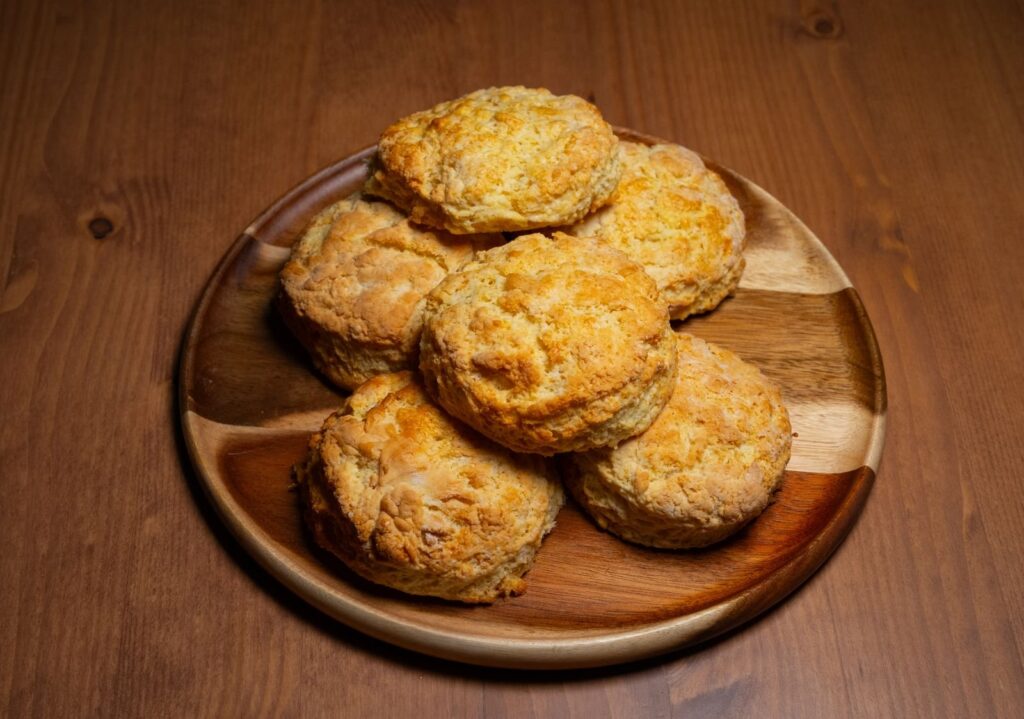 Golden homemade biscuits piled on a round wooden board