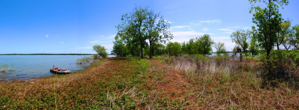 Grapevine Lake shoreline with a small boat pulled up beside grassy banks