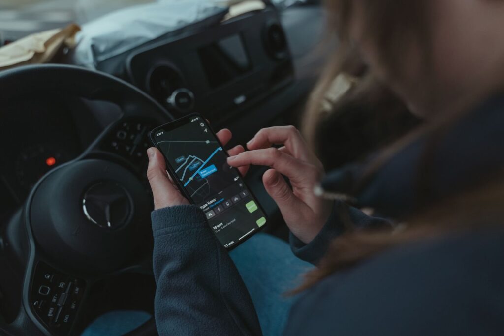 Hands holding a smartphone with a navigation map inside a car