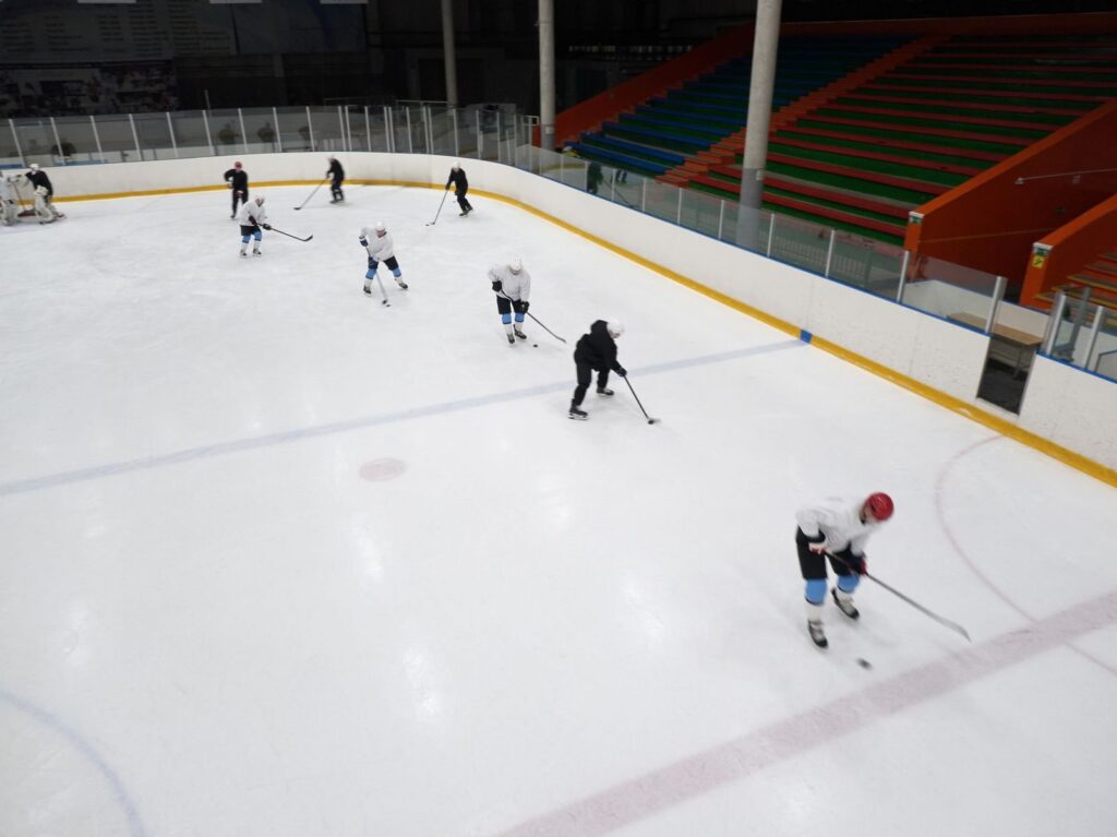 Hockey players run drills during a practice session on an indoor ice rink
