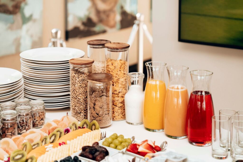 Hotel breakfast table with cereal jars, juice carafes and cut fruit