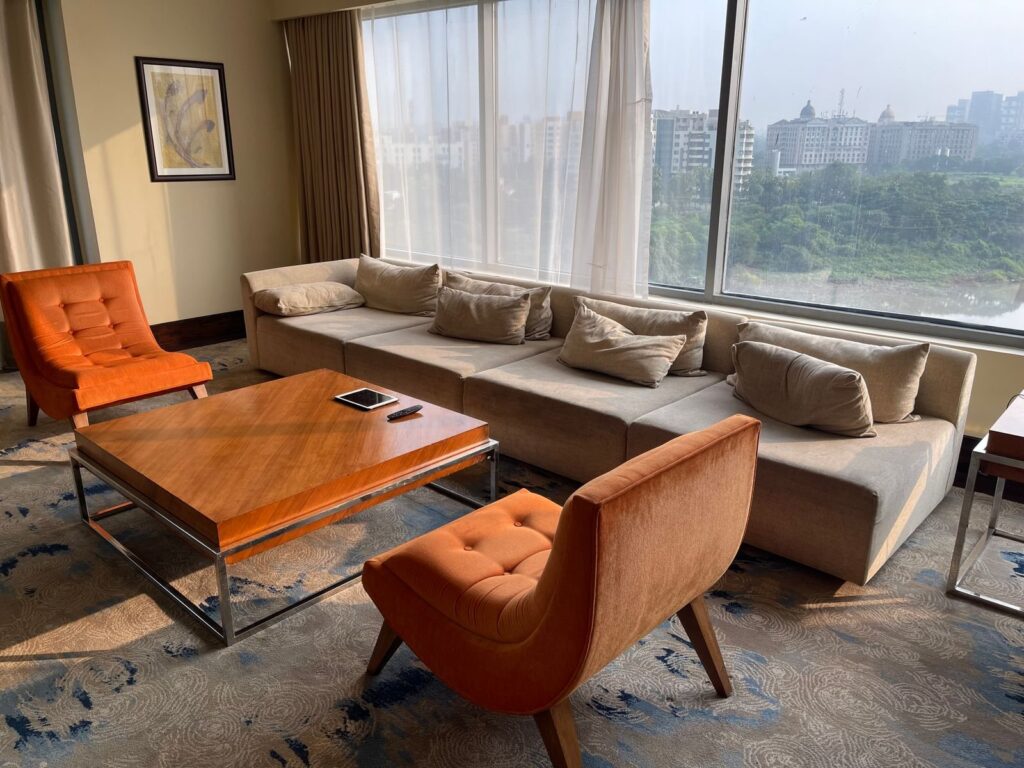 Hotel suite living area with a sectional sofa and floor-to-ceiling windows
