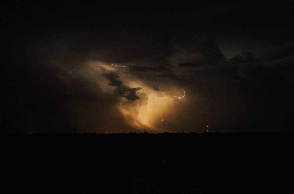 Lightning glowing through storm clouds over dark Texas countryside at night