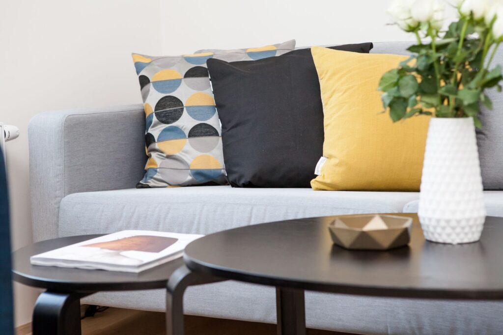 Living room with a gray sofa and yellow cushions like you'd find in a Frisco TX Airbnb