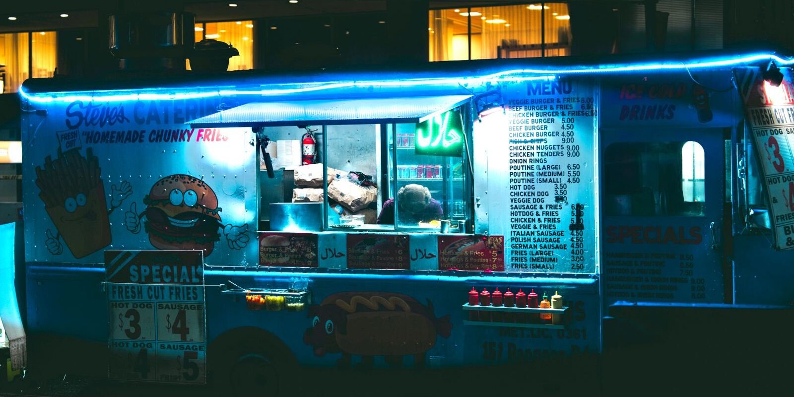 Neon-lit food truck with a menu board, like the food trucks in Frisco TX you find after dark