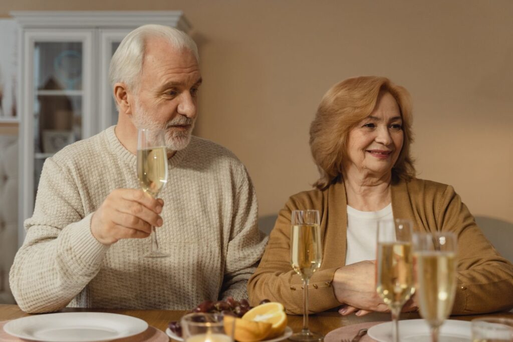 Older couple raising champagne glasses at a family dinner table