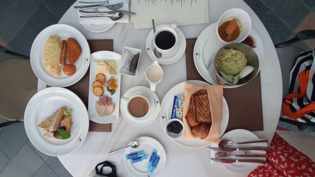 Overhead view of a hotel breakfast table with eggs, toast, pastries and coffee