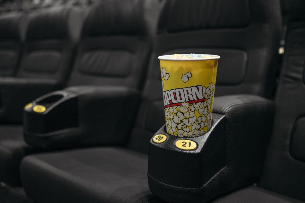 Popcorn bucket in the cupholder of a black leather cinema recliner
