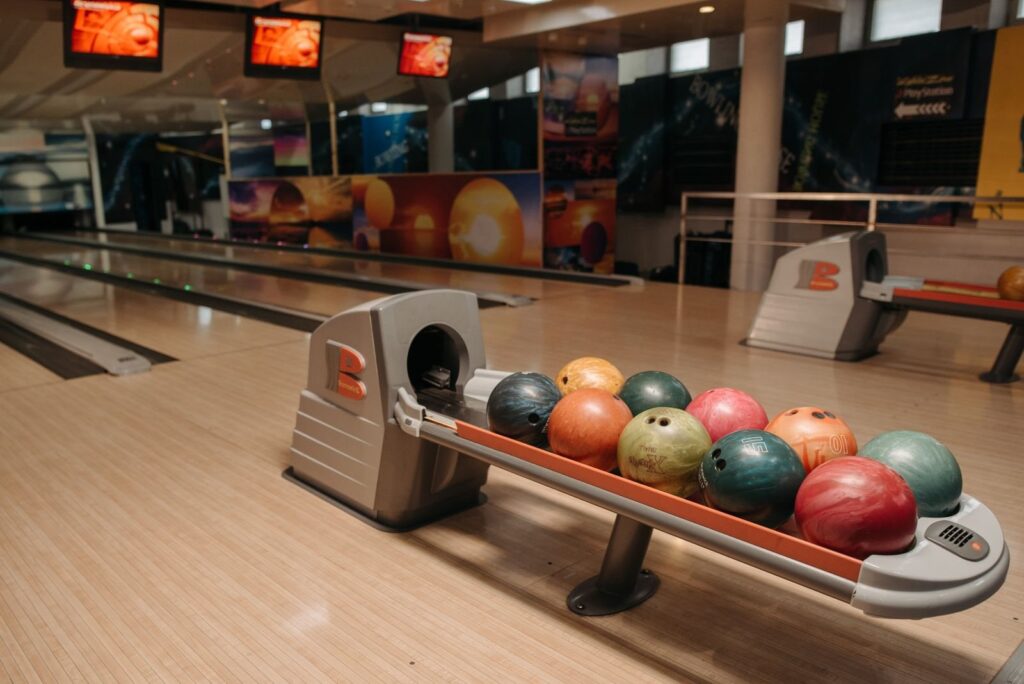 Rack of colorful house bowling balls on a ball return between two lanes