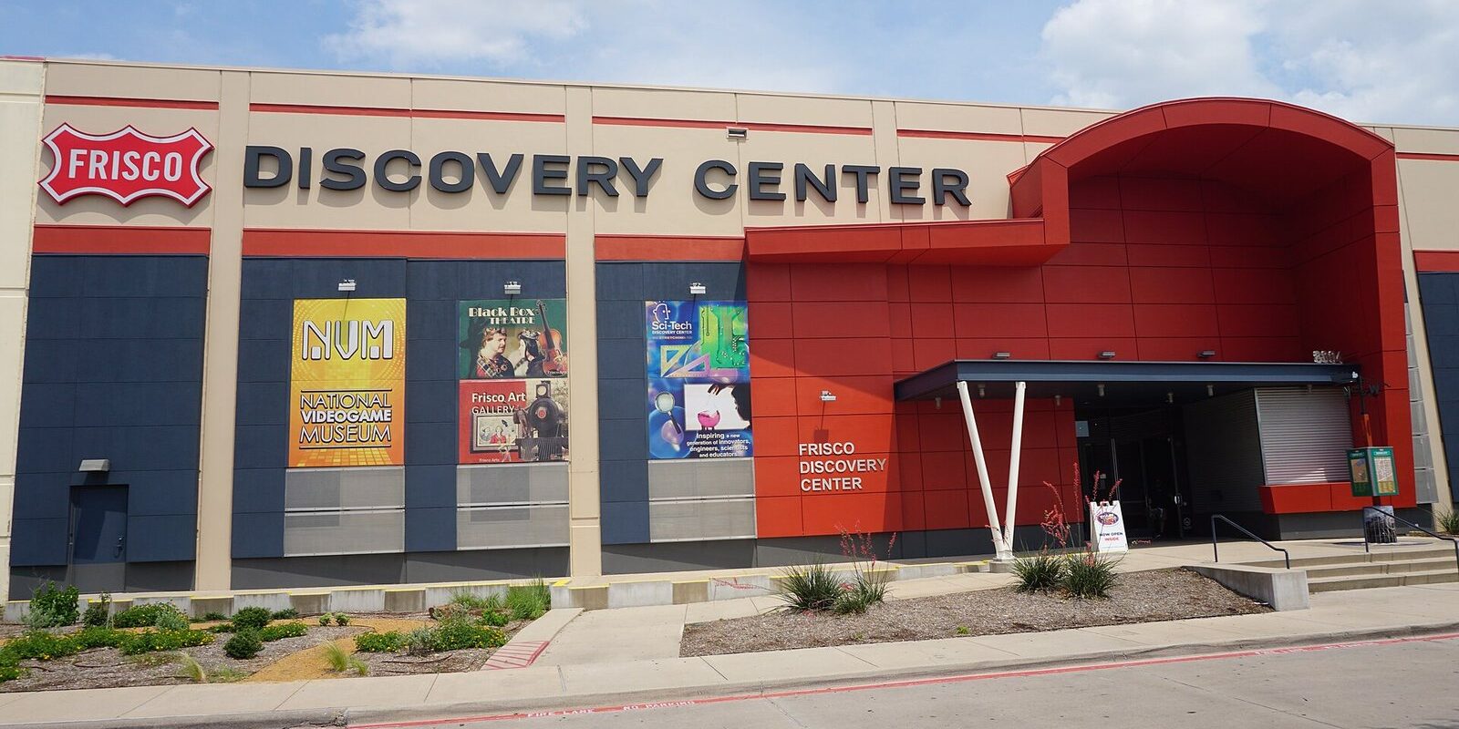 Red and blue entrance of the Frisco Discovery Center with exhibit banners on the front wall