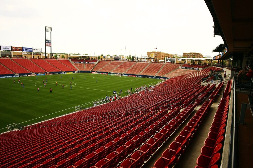 Red stadium seats curving around a soccer pitch at Toyota Stadium in Frisco