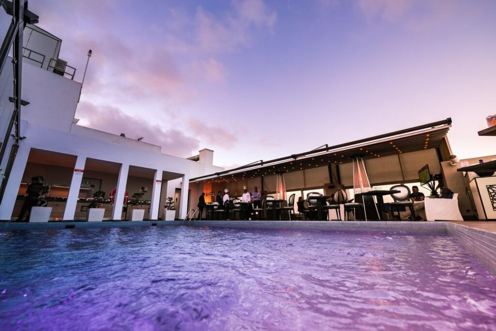 Rooftop hotel pool at dusk with lounge seating along the deck
