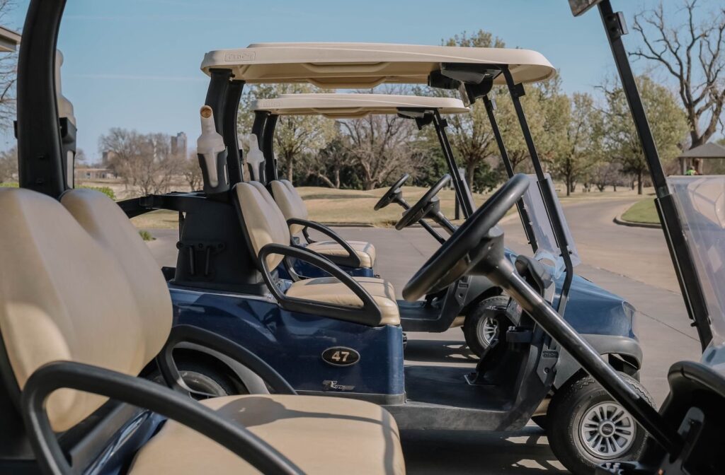 Row of white golf carts parked on a paved lot on a sunny morning