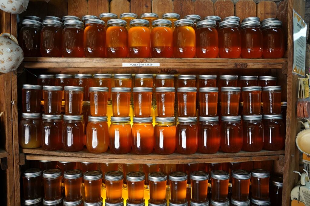 Rows of amber honey jars stacked on wooden shelves at a market stand
