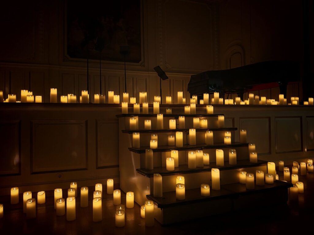 Rows of flickering candles lit on a dark staircase inside a hall