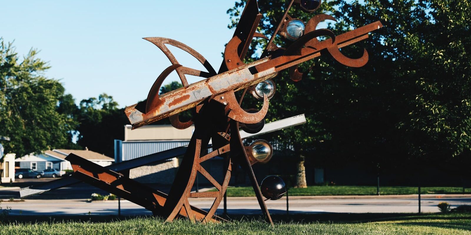 Rusted steel abstract sculpture on a lawn, like the modern works at the Texas Sculpture Garden in Frisco