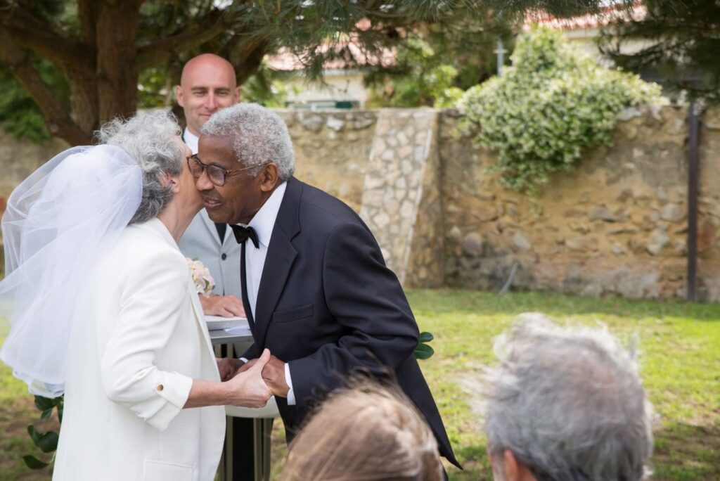 Silver-haired couple embracing during an outdoor vow renewal ceremony
