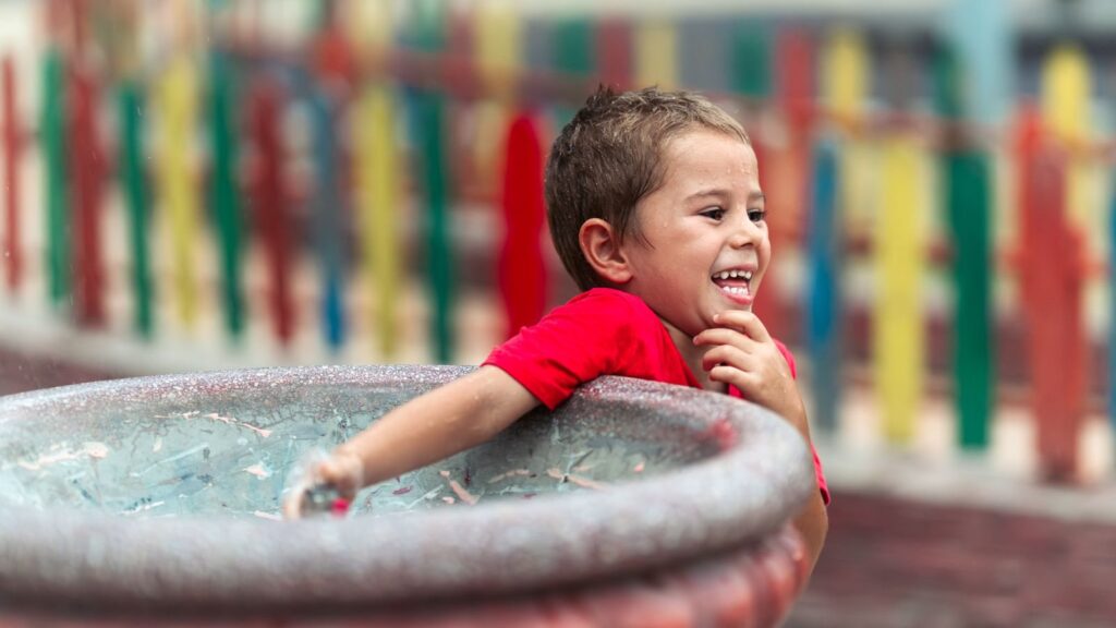 Smiling boy leaning on a fountain basin while playing with water outdoors