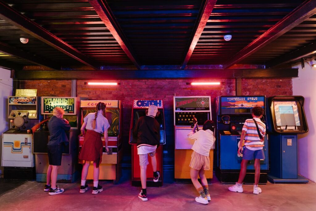 Teens playing a row of retro arcade cabinets, the classic side of teen activities in Frisco TX