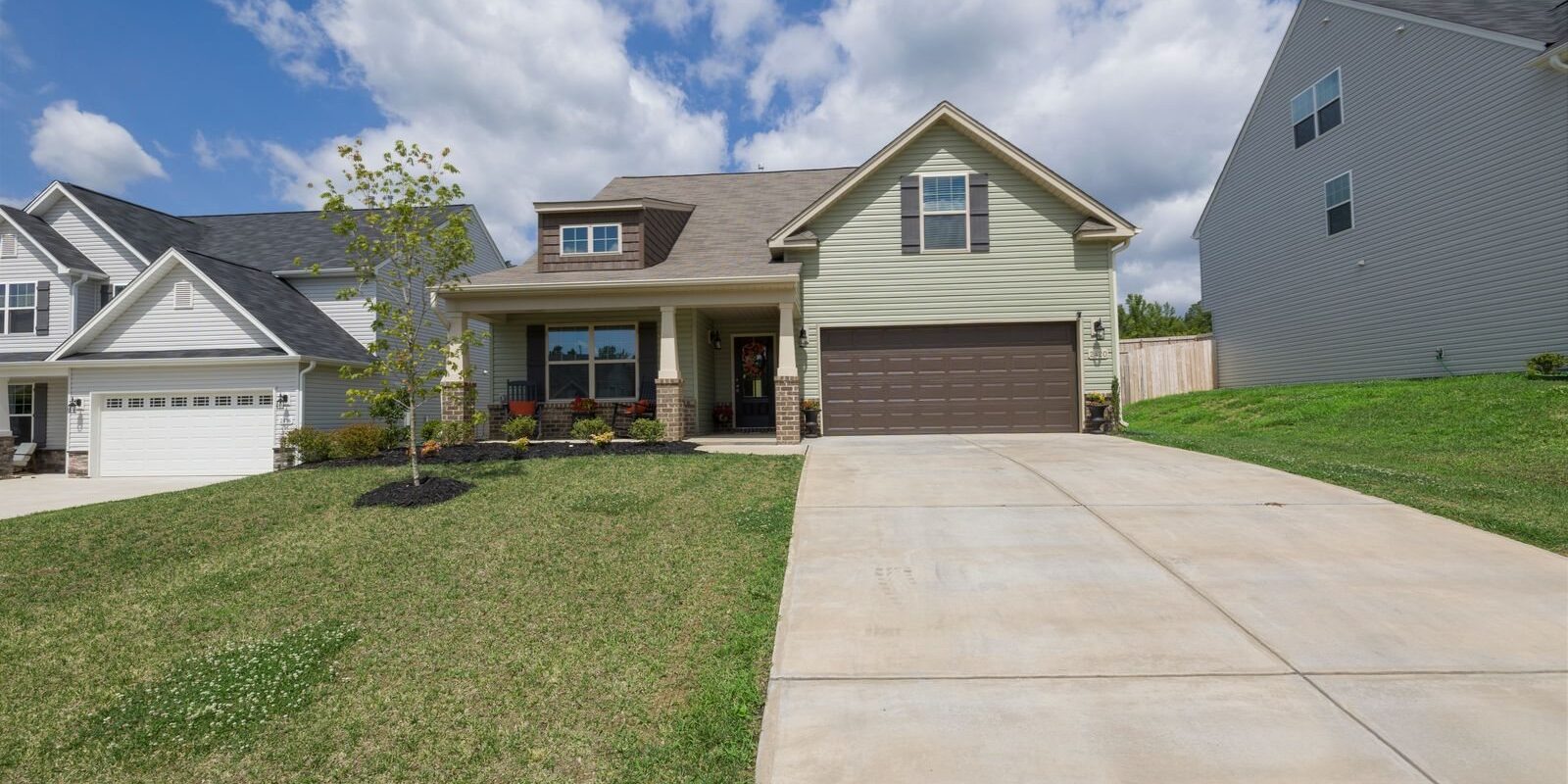 Two-story suburban house with a two-car garage, a wide concrete driveway and a small front lawn