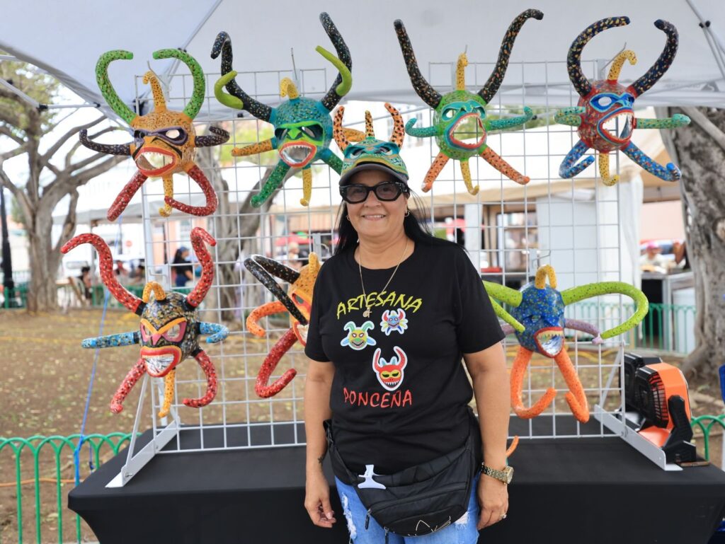Vendor with colorful handmade masks at an outdoor craft booth like those at Frisco TX art events