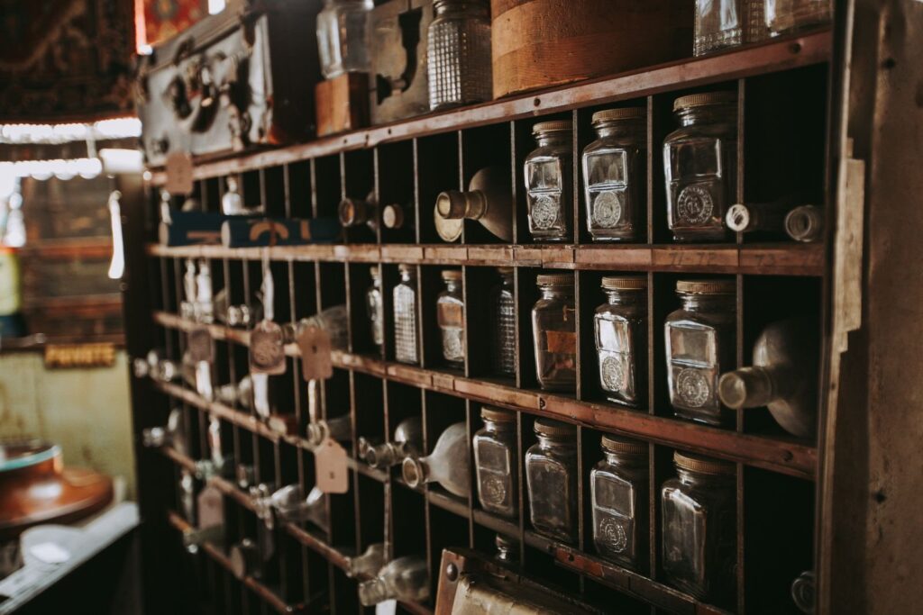 Vintage glass bottles lined up in the cubbies of an old wooden shelf