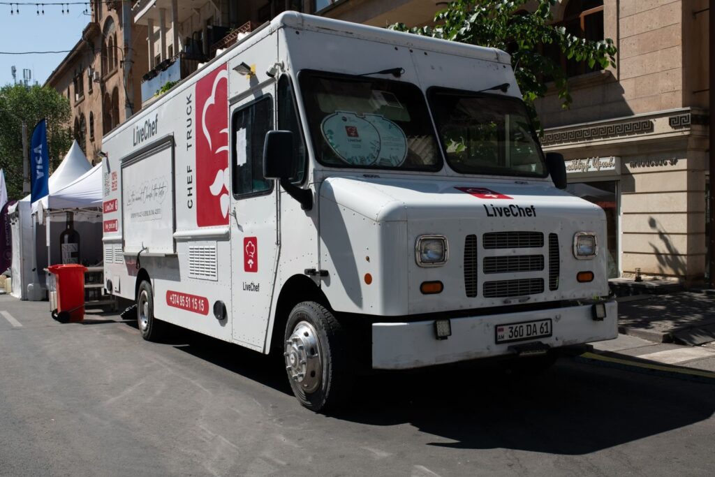 White catering food truck parked beside tents at a street festival