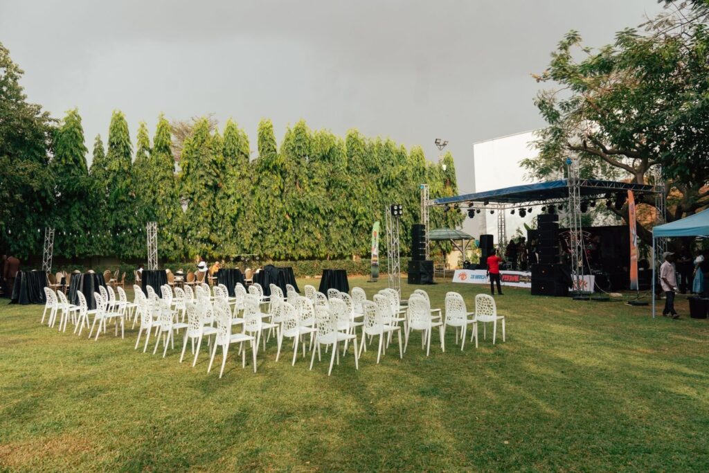 White chairs set out on a lawn in front of a small outdoor stage with sound equipment
